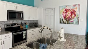 A kitchen with white cabinets, a stainless steel sink, a microwave, a stove, and a toaster. - Near Disney 4Bd/3Ba Villa w/ Private Pool, Hot Tub in Gated Resort Community (Kissimmee)