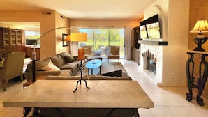 A spacious living room with a sofa, coffee table, and fireplace. - Prestigious Fairway Living – Luxe 2BR on 7th Hole, Mission Hills (Rancho Mirage)
