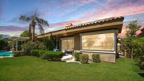 A modern house with a large patio, a swimming pool, and a well-maintained lawn. - Prestigious Fairway Living – Luxe 2BR on 7th Hole, Mission Hills (Rancho Mirage)
