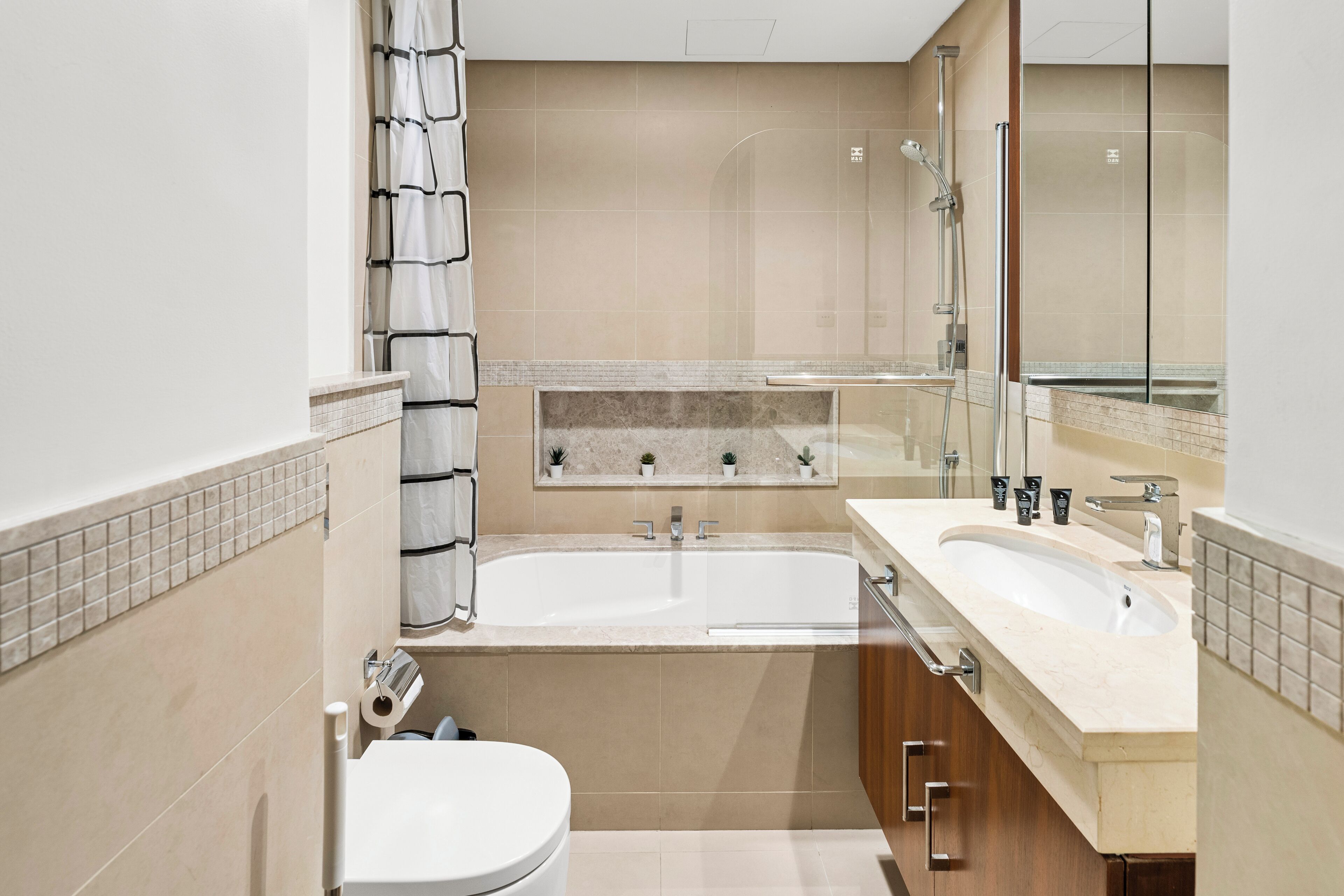 Une salle de bain moderne équipée d’une baignoire, de deux lavabos, de toilettes et d’une douche.