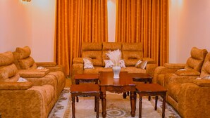 A living room with a sofa set, a coffee table, and a chandelier. - Lux Suites Lions Den Holiday Homes (Nakuru)