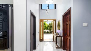 A hallway with a modern kitchen area, a wooden door, and a view of a garden.