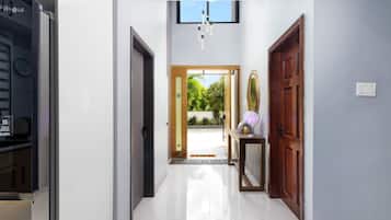 A hallway with a modern kitchen area, a wooden door, and a view of a garden.