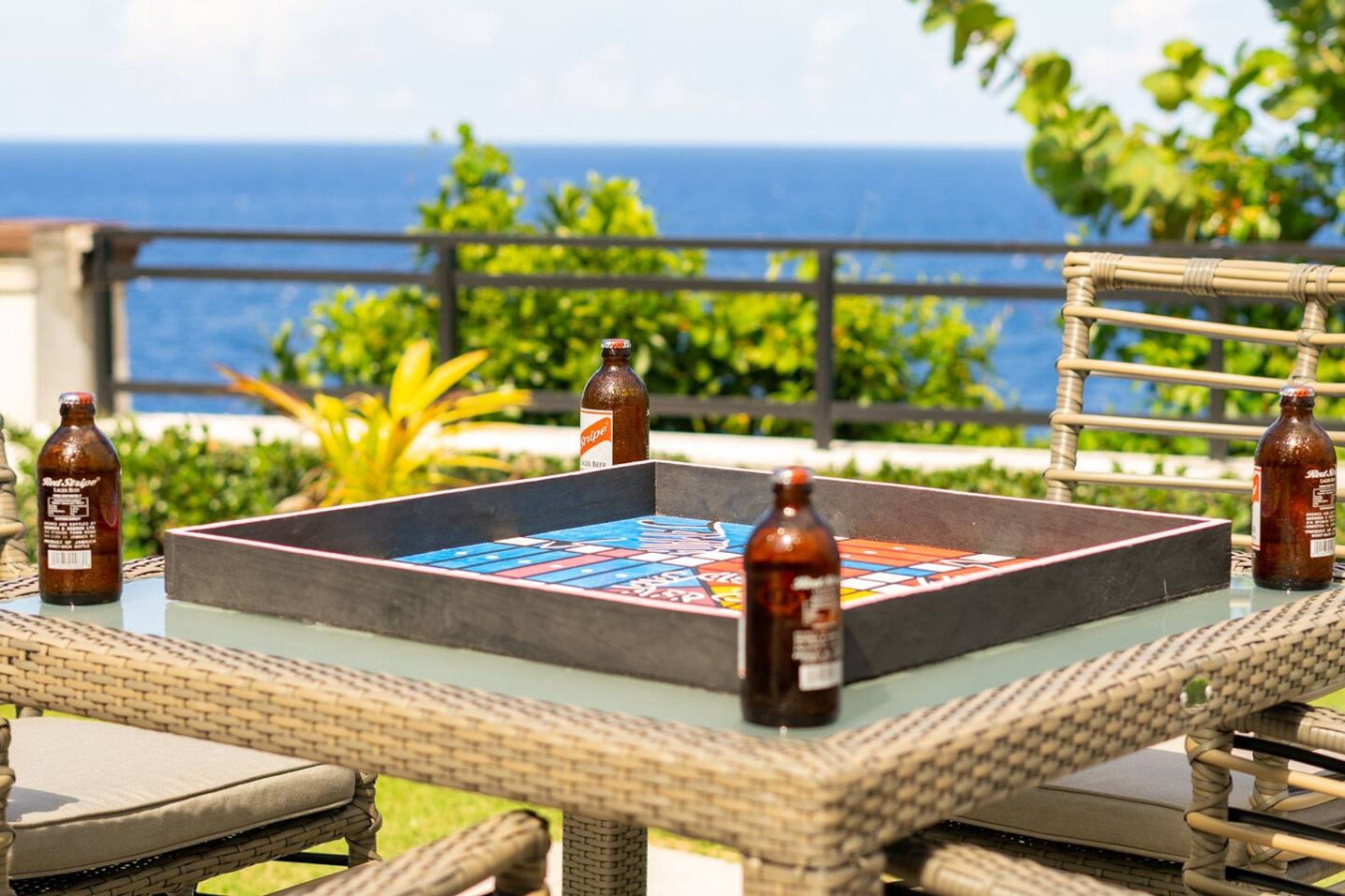 Ein Tisch mit einem Brettspiel und Bierflaschen, auf einem Balkon mit Blick auf den Ozean.