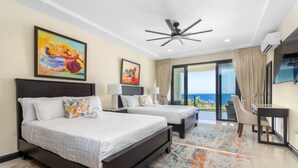 Une chambre d’hôtel avec deux lits, un ventilateur de plafond, une télévision et un balcon avec vue.