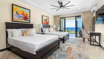 A hotel room with two beds, a ceiling fan, a TV, and a balcony with a view.