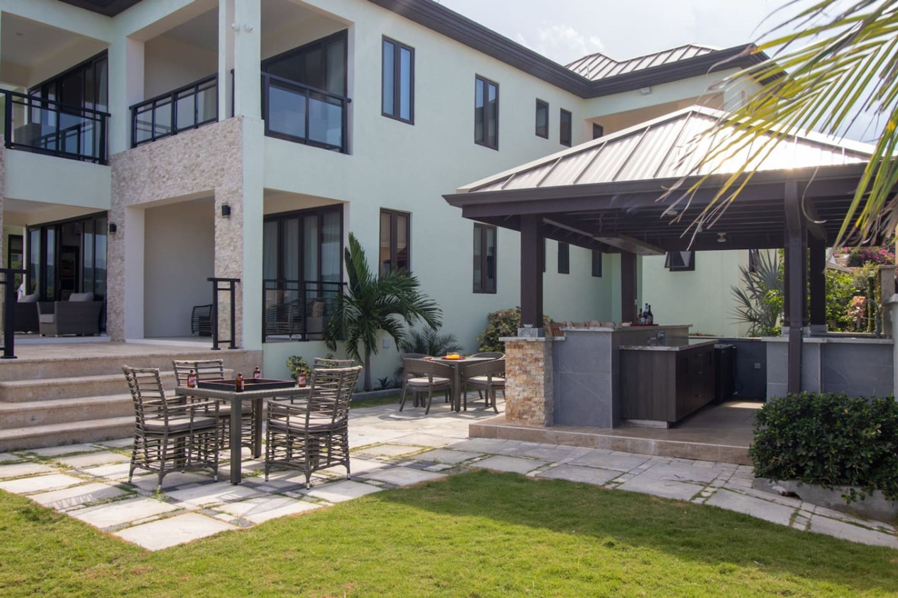 A modern two-story house with a patio area featuring outdoor furniture and a barbecue grill.