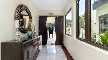 A hallway with a dark wooden cabinet, a large mirror, and an exit sign.
