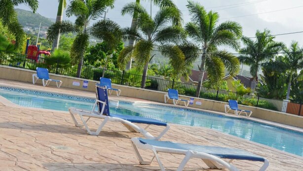 A swimming pool with lounge chairs and palm trees in the background. - 3 King Beds Drax Hall Pool Gym Gated Full Air Con (Ocho Rios)