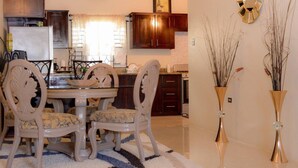 A dining area with a round table, four chairs, and a rug. - 3 King Beds Drax Hall Pool Gym Gated Full Air Con (Ocho Rios)