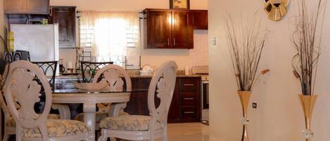 A dining area with a round table, four chairs, and a rug.