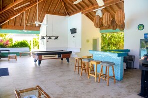 Un espace piscine comprenant une table de billard, des tabourets de bar et un bar.