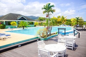 Un espace piscine avec des chaises longues et une terrasse en bois.