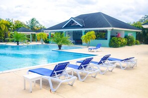 Un espace piscine avec des chaises longues et une structure abritée.