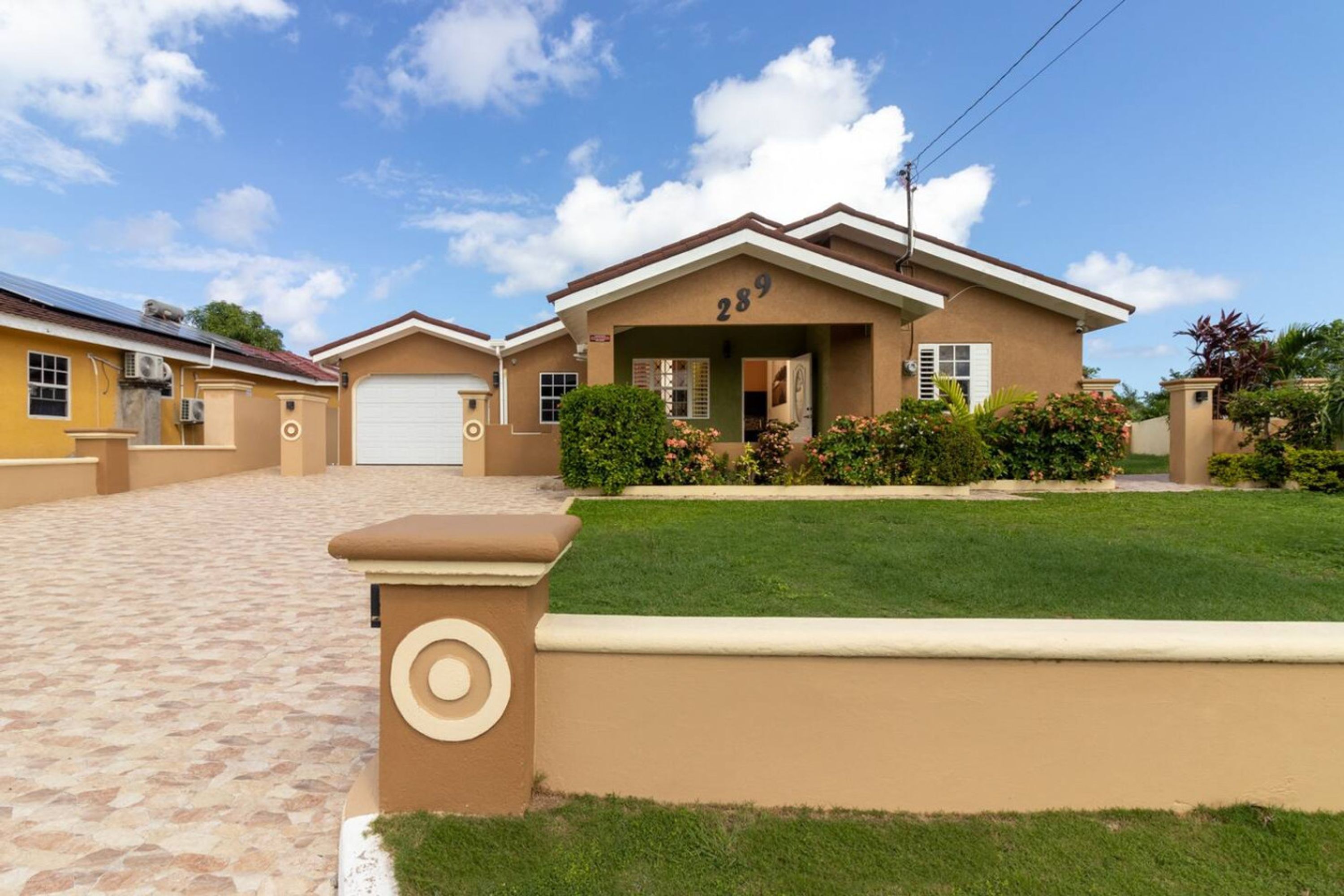 A residential house with a garage, a well-maintained lawn, and a clear sky.