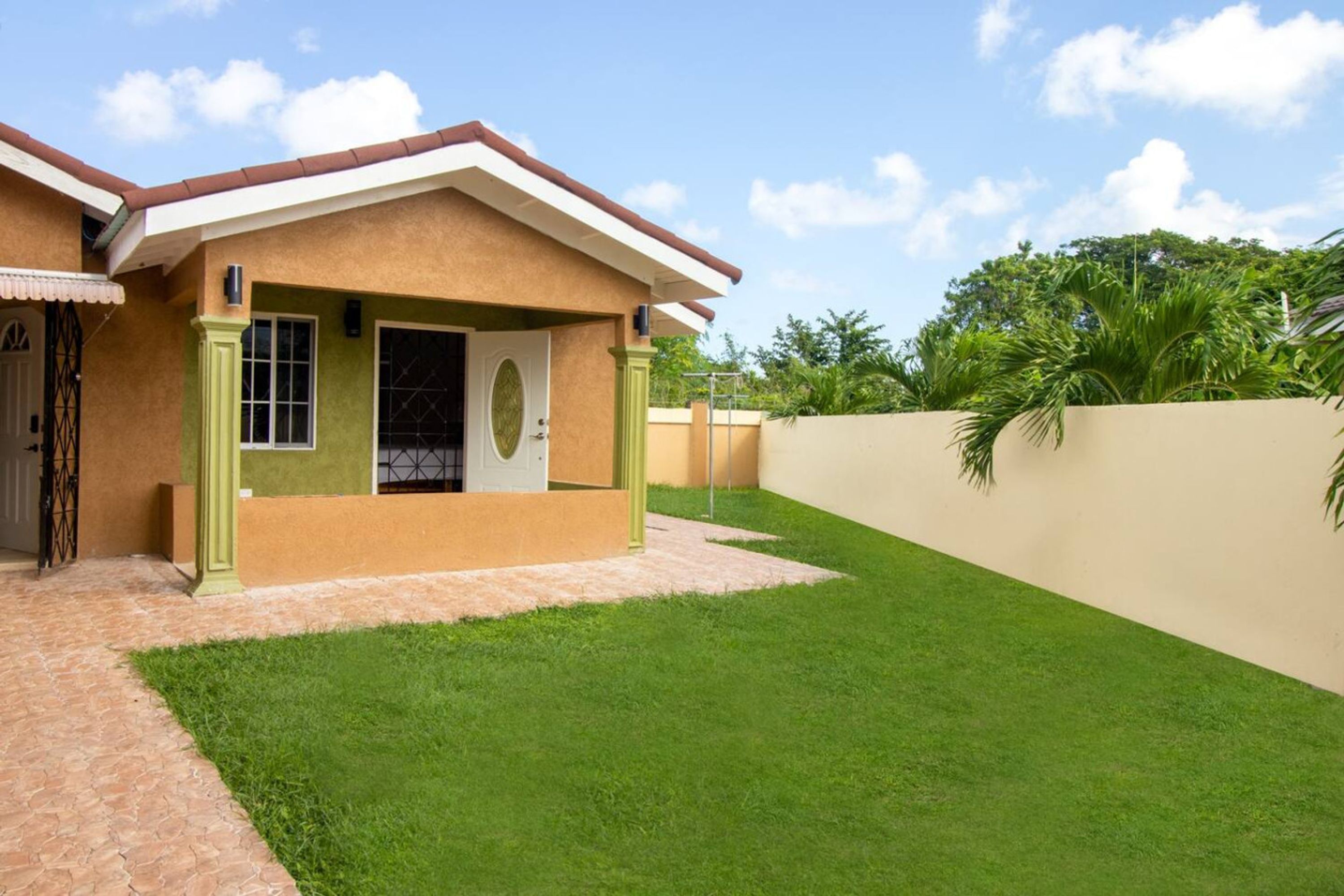Une maison avec une pelouse bien entretenue, une construction à un seul étage et une façade de couleur beige.