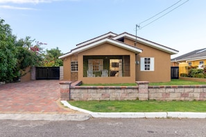 A single-story house with a brick driveway, a stone retaining wall, and a small front yard. - Private Pool Draxhall Gated Gym Tennis Full AC (St. Ann's Bay)