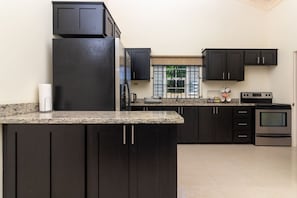A modern kitchen with dark cabinetry, a granite countertop, and stainless steel appliances. - Private Pool Draxhall Gated Gym Tennis Full AC (St. Ann's Bay)
