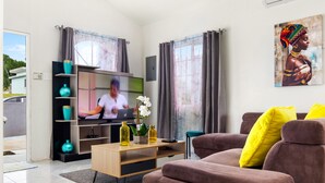 A modern living room with a brown sofa, a wooden coffee table, and a flat-screen TV. - Comfort Arecahomes Beach Access Pool Waterpark (Discovery Bay)
