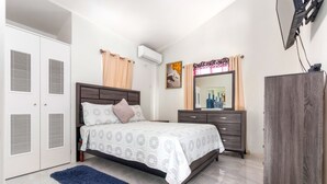 A bedroom with a bed, a dresser, a wardrobe, and an air conditioning unit. - Comfort Arecahomes Beach Access Pool Waterpark (Discovery Bay)