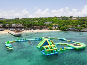 Una playa con estructuras para juegos acuáticos y una zona con sombrillas.