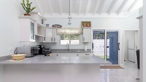 Una cocina moderna con gabinetes blancos, una isla grande y vistas al exterior.