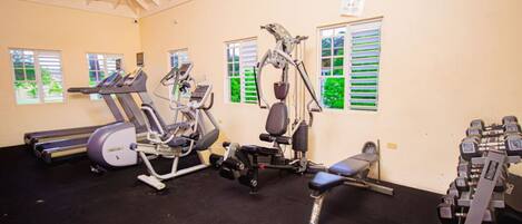 A gym with treadmills, elliptical machines, a bench press, and dumbbells.