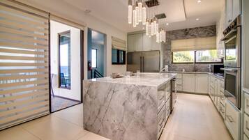 A modern kitchen with a marble island, stainless steel appliances, and pendant lighting.