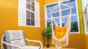 A room with a white wicker chair, a macramé hanging chair, and a potted plant. - Drax Hall Pool Gym Gated Tennis Kidsplygrnd 304 (Ocho Rios)