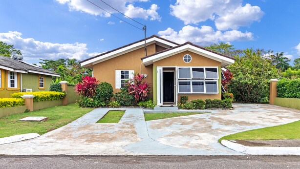 A residential house with a front yard, a driveway, and a well-maintained lawn. - Drax Hall Pool Gym Gated Tennis Kidsplygrnd 304 (Ocho Rios)