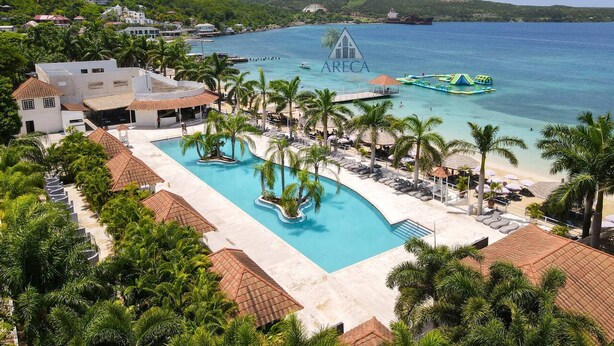 Un resort con una piscina grande, zona de playa y vista al océano.