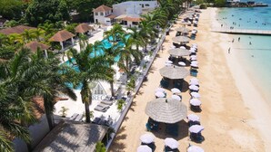 Un resort con piscina, playa y sombrillas.