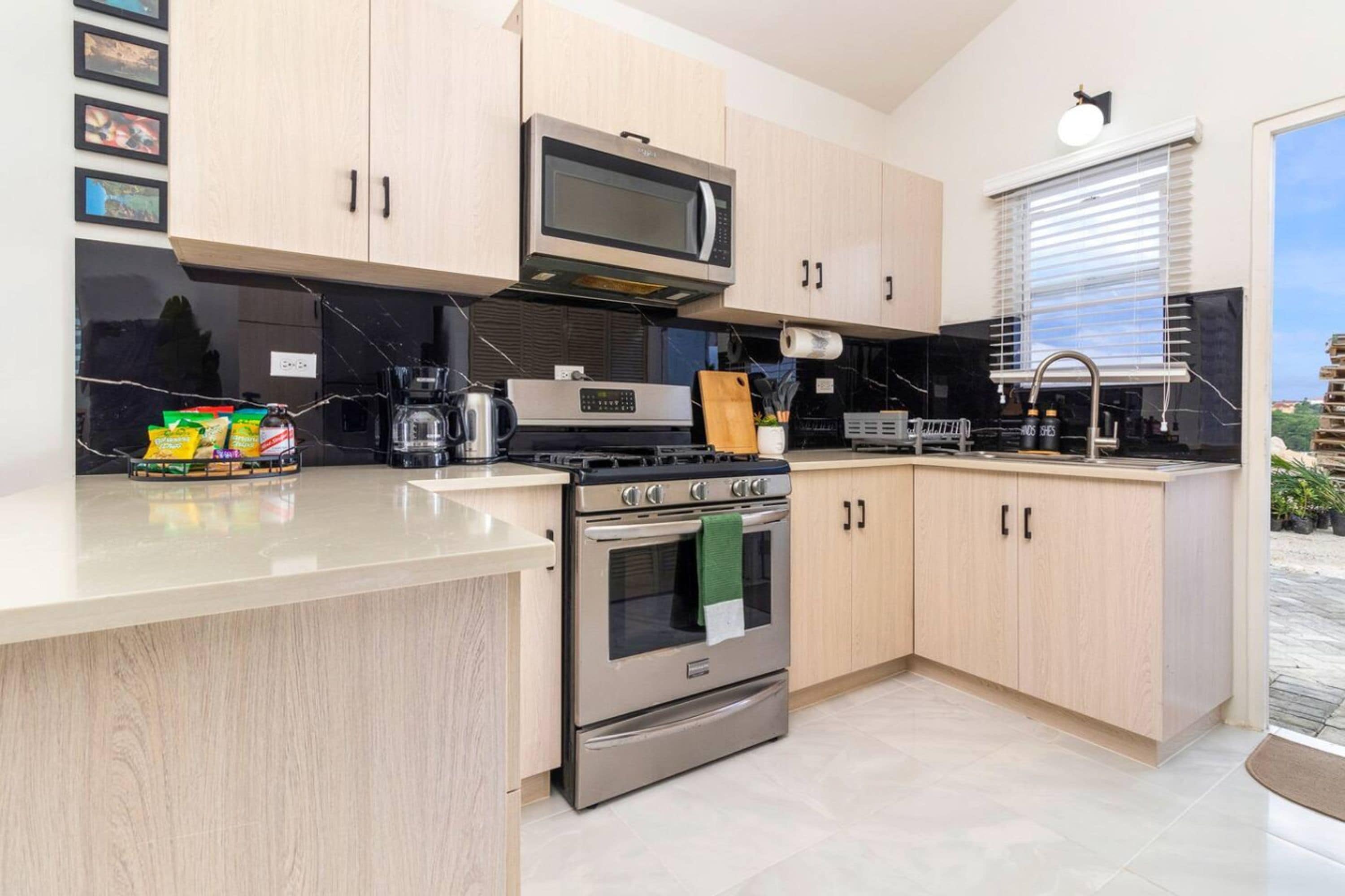 A modern kitchen with stainless steel appliances, wooden cabinets, and a large window.