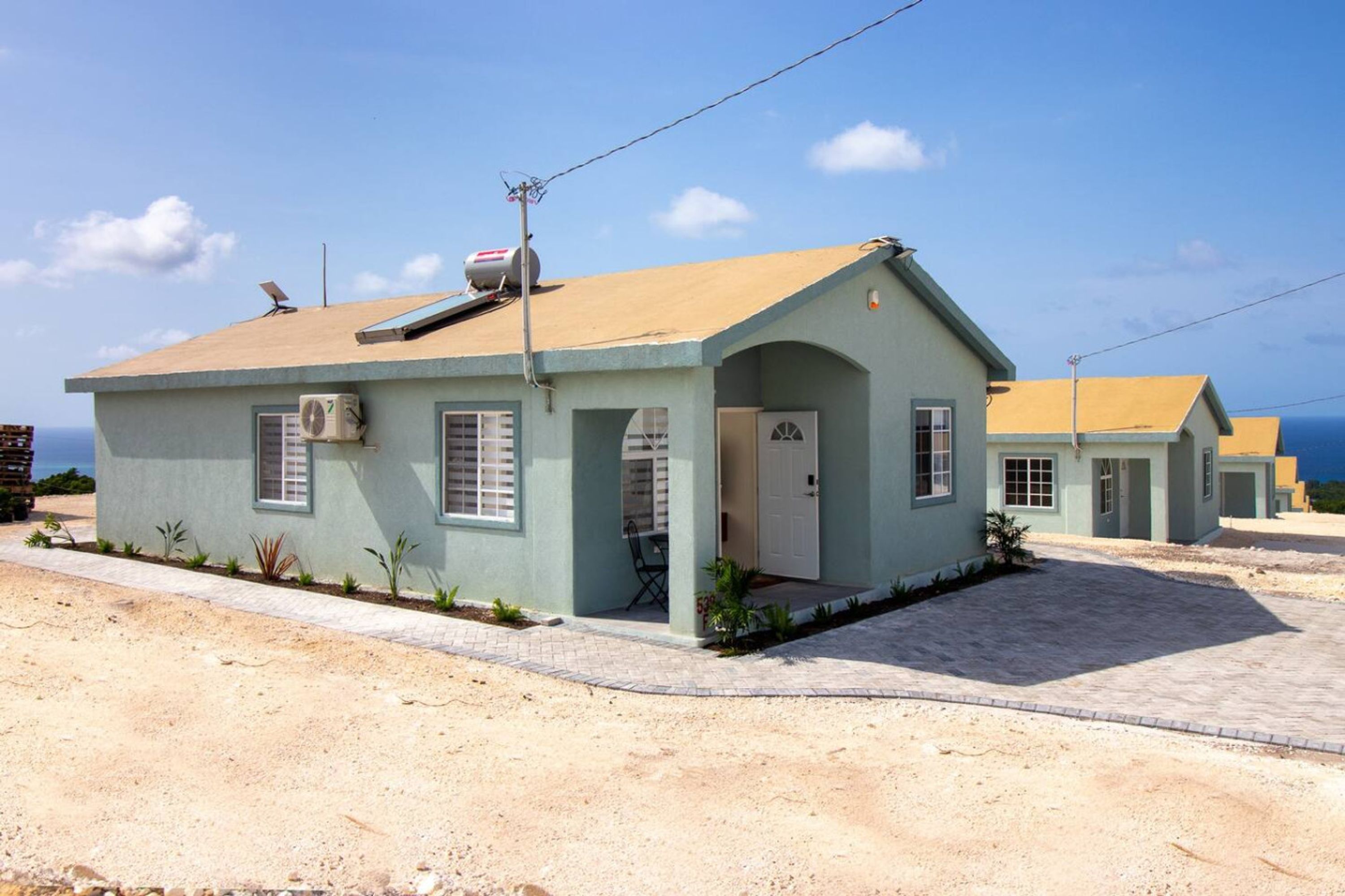 A two-story building with a flat roof, a small porch, and a door.