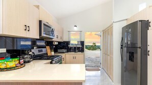Una cocina moderna con una isla central, electrodomésticos integrados y vistas al exterior.
