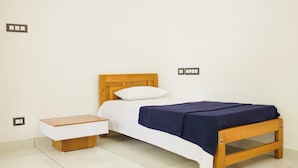 Ein Schlafzimmer mit einem hölzernen Bett, weißer Bettwäsche und einem Nachttisch.