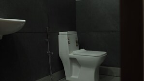 Ein Badezimmer mit Toilette, Waschbecken an der Wand und Duschbereich.