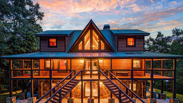 A two-story log cabin with a central entrance, two staircases, and a covered deck.