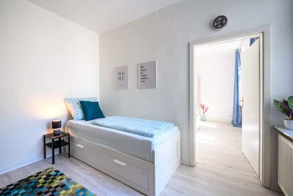 Un dormitorio con cama, mesita de noche y una alfombra pequeña.