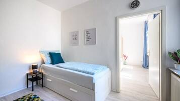 Un dormitorio con cama, mesita de noche y una alfombra pequeña.