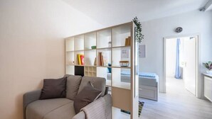 A modern living room with a grey sofa, a bookshelf, and a small table.