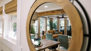 Un intérieur moderne comprenant un coin repas, un canapé et un grand miroir qui reflète la pièce.