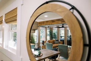 Un intérieur moderne comprenant un coin repas, un canapé et un grand miroir qui reflète la pièce.