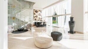 A spacious living area with a modern staircase, a fireplace, and a large window offering a view of the outdoors. - Beachfront Peninsula PV 8th Floor (Puerto Vallarta)