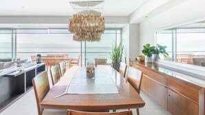 A spacious dining area with a large wooden table, modern chairs, and a unique hanging light fixture. - Beachfront Peninsula PV 8th Floor (Puerto Vallarta)