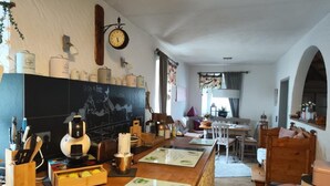 Une cuisine chaleureuse avec un bar en bois, une horloge et divers ustensiles de cuisine.