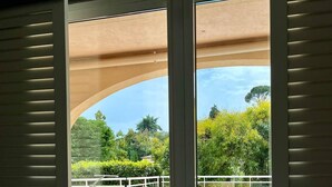 A room with a sliding glass door leading to an outdoor swimming pool area with a tiled deck and a view of greenery. - Villa on the hills of Mandelieu with sea view and swimming pool (Mandelieu-la-Napoule)