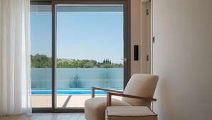 A room with a sliding glass door leading to a balcony with a pool view. - VILA1 ANAPNOE IKIES CORFU WITH PRIVATE POOL (Corfu)