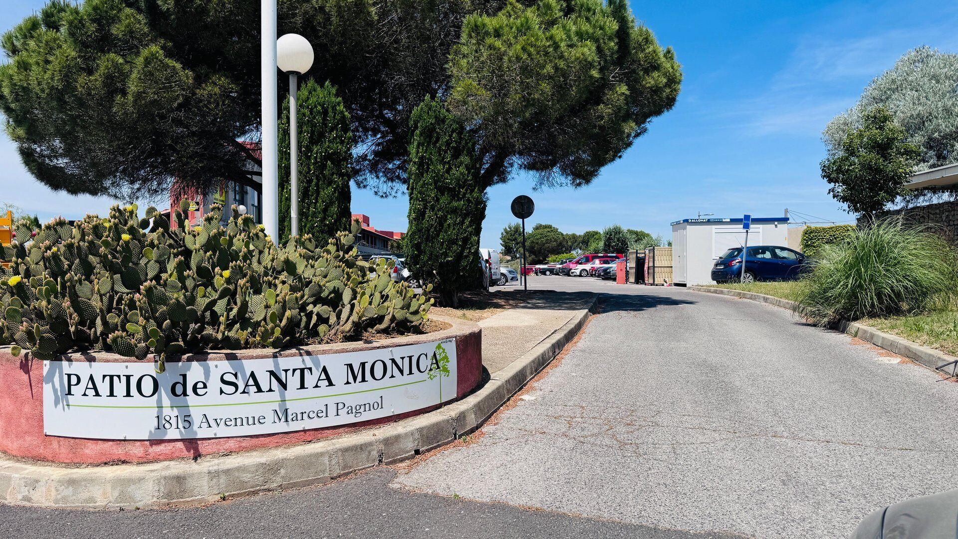 A street sign for 'Patio de Santa Monica' with a cactus garden and a clear sky.