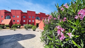 Un bâtiment rouge avec de nombreuses fenêtres et une allée gravillonnée.